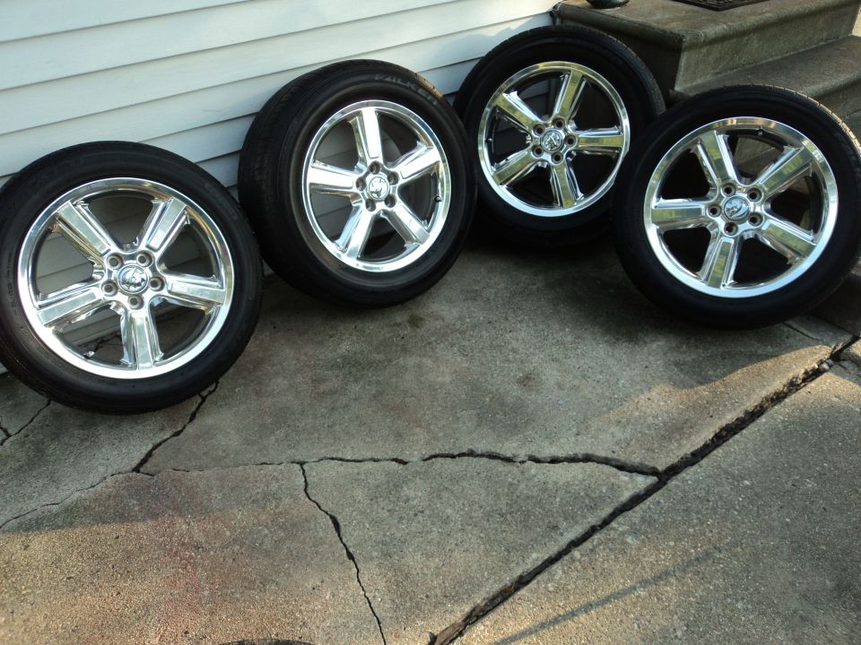 Four chrome 5-spoke wheels with black tires on cracked concrete