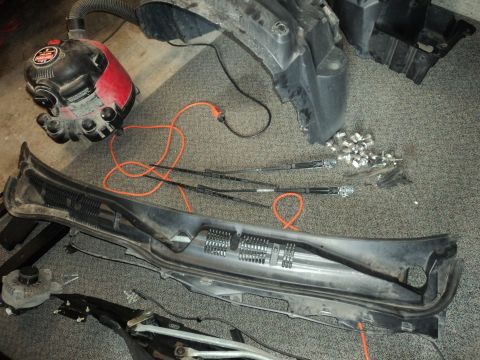2004 Mercury Grand Marquis - Various car parts are disassembled and laid out on a carpeted surface, including a shop vacuum and windshield wipers.