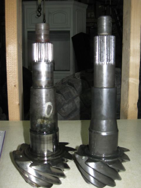 1990 Ford Bronco - Two differential gears are shown, one with a white mark, against a background of tires and cabinetry.