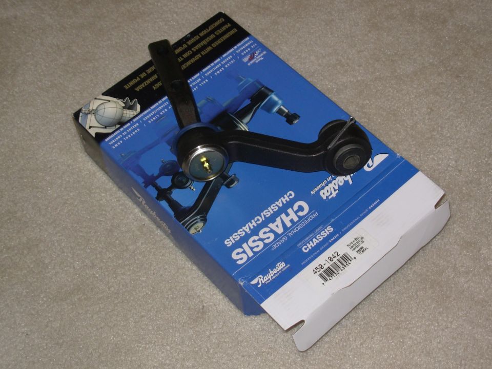 Raybestos control arm with ball joint sitting atop its blue chassis parts box