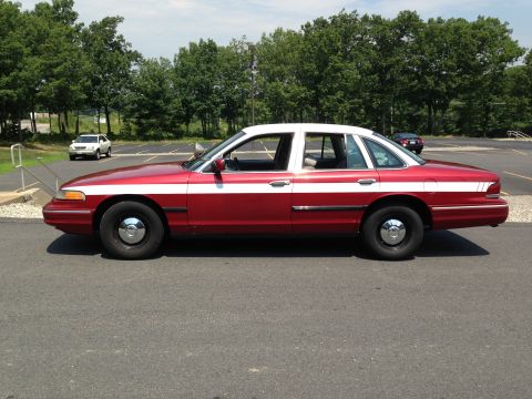 2004 Ford Crown Victoria - Side view of a red and white 2004 Ford Crown Victoria sedan parked in a lot.