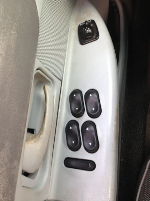 2004 Ford Crown Victoria - Close-up of car door's interior panel showing power window and mirror controls.