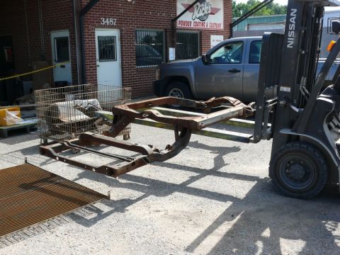1976 Chevrolet Corvette - A rusted vehicle frame is being lifted by a forklift outside a building with a "Rick's Powder Coating & Customs" sign.