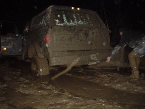 1995 Ford Bronco - This SUV is stuck deep in the mud, with a person attempting to free it.