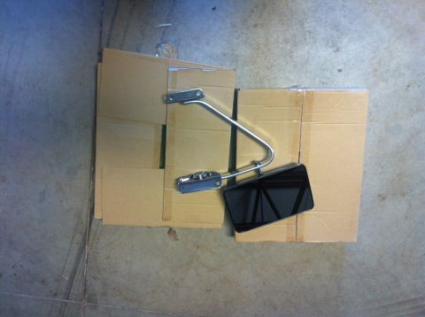 1982 Ford Bronco - Side mirror assembly, likely for a classic vehicle, is presented on a bed of cardboard boxes.