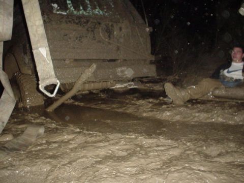 1995 Ford Bronco - A person sits in a muddy vehicle that is stuck in water, with a tow strap attached.