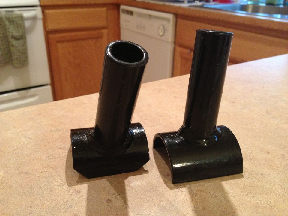 Two black metal parts, possibly for a Jeep Wrangler roll cage, on a countertop