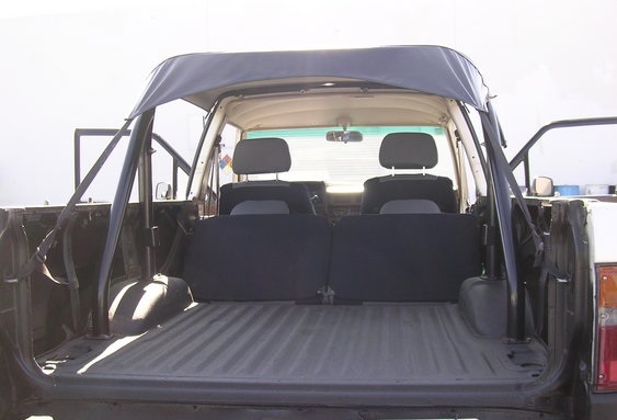 Back view of a pickup truck's interior, showing the bed, rear seats, and soft top