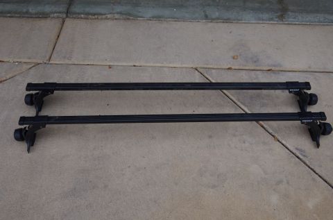 1983 Ferrari Enzo - Two black Thule roof rack crossbars are laid out on a concrete surface.