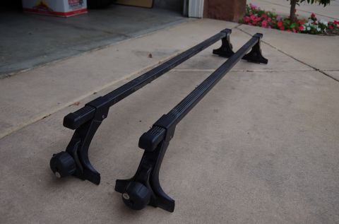 1983 Ferrari Enzo - Two black roof rack crossbars are shown on a concrete surface, likely for sale or storage.