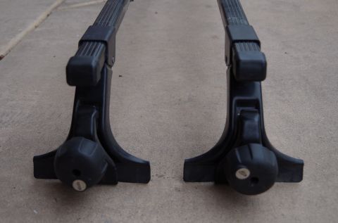 1983 Ferrari Enzo - Two black roof rack crossbars are shown resting on a concrete surface.