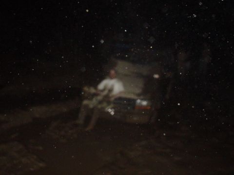 1995 Ford Bronco - A person sits on the hood of a 1995 Ford Bronco at night, with the vehicle appearing to be stuck.