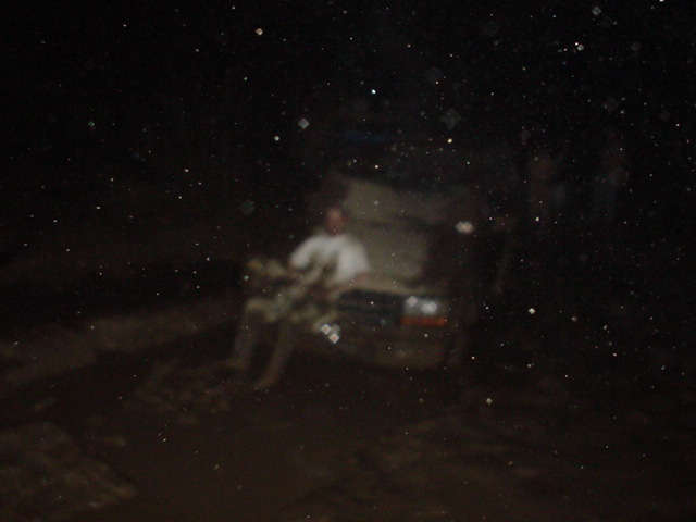 Blurry dark night photo of a person beside a large vehicle