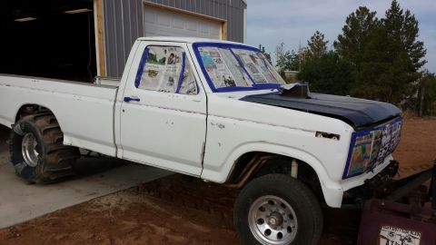 1995 Ford Bronco - A white pickup truck is parked in front of a garage, undergoing preparation for painting.