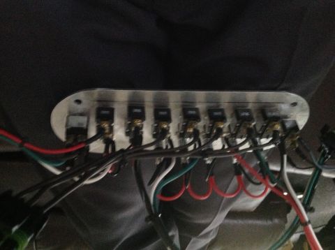 1961 International Scout 800 - A close-up view of an aftermarket switch panel with numerous wires connected to toggle switches.