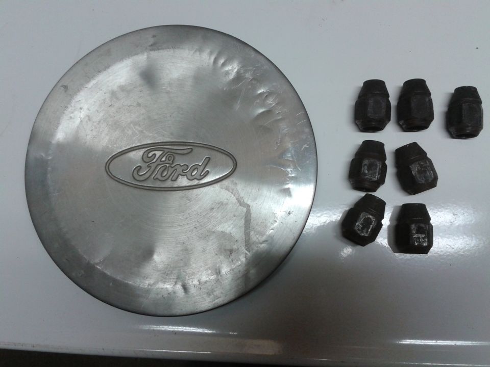 Ford oval logo on a metal hubcap, plus seven lug nuts