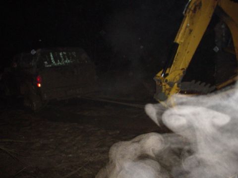 1995 Ford Bronco - An excavator appears to be assisting a stuck vehicle in the dark.