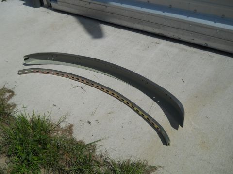 1992 Ford Bronco - Two curved metal trim pieces are shown lying on a concrete surface next to some grass.