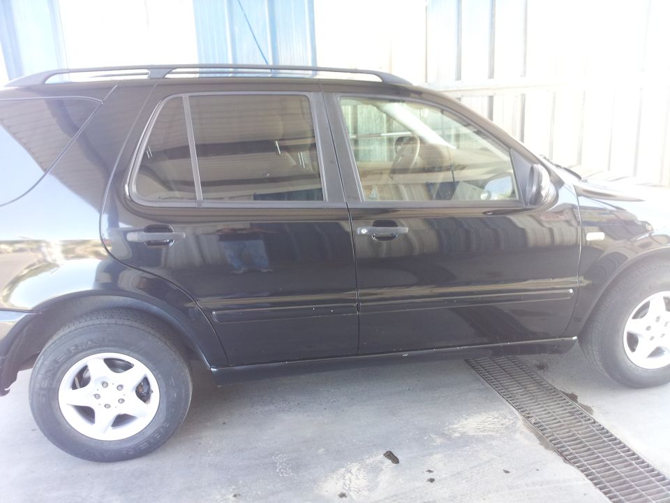 Side view of a black 2000 Mercedes-Benz ML-Class SUV parked on a concrete surface