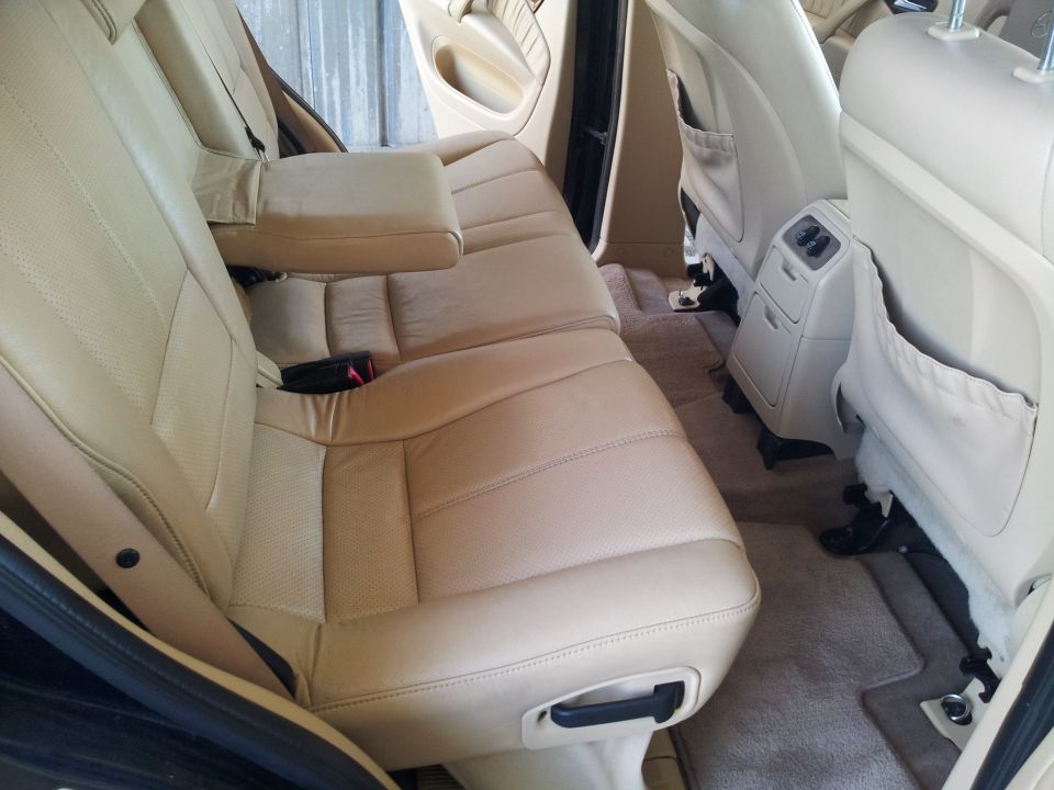 Back seats and floor of a car, showing tan leather upholstery and carpet