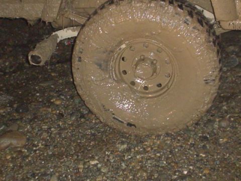 1995 Ford Bronco - Vehicle stuck in mud, showing a heavily soiled tire and exhaust pipe.