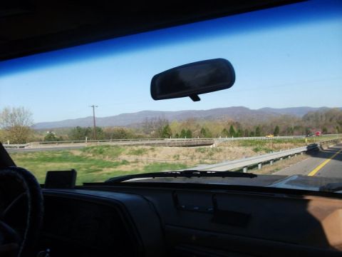 1990 Ford Bronco - Driving on a highway with a view of mountains and trees under a clear blue sky.