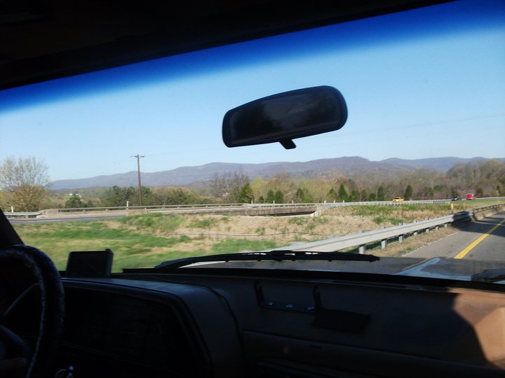 View from inside a vehicle driving on a highway with mountains in the distance