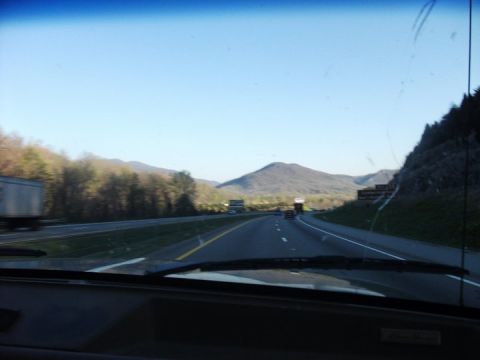 1990 Ford Bronco - A view from inside a vehicle driving on a highway through a mountainous landscape with other traffic.