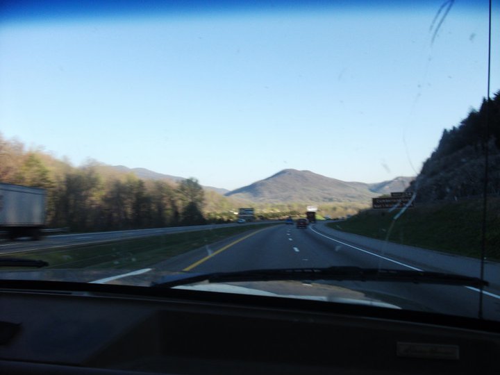 Highway view from inside a vehicle, with mountains and other vehicles on the road