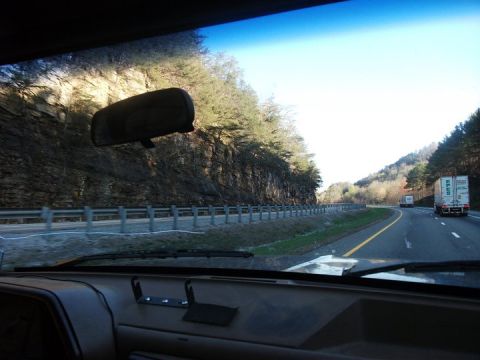 1990 Ford Bronco - Driving on a highway with a cliff face on one side and other vehicles on the road.