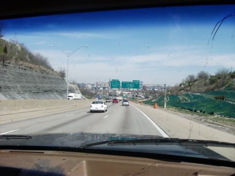 1990 Ford Bronco - View from inside a vehicle driving on a highway with other cars and a distant city visible.