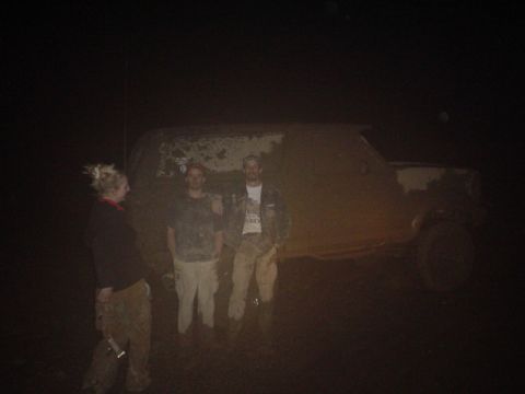 1995 Ford Bronco - Three individuals stand next to a heavily mud-covered SUV, suggesting it may be stuck.