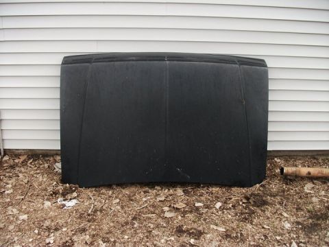 1990 Ford Bronco - Hood part for a vehicle, placed outdoors against a white wall.