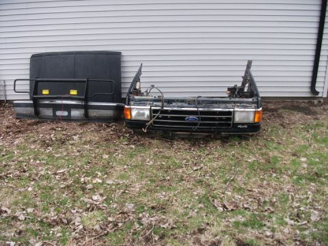 1990 Ford Bronco - The front end of a Ford truck, including the grille and hood, is disassembled and placed outside.