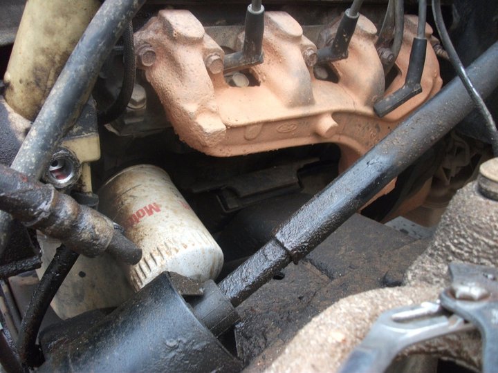 Engine bay showing an oil filter and exhaust manifold with visible Ford logo