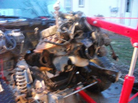 1990 Ford Bronco - An engine is being lifted out of a vehicle using an engine hoist.