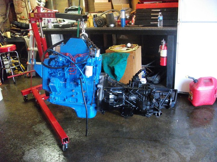 blue engine and black transmission on engine stand in garage