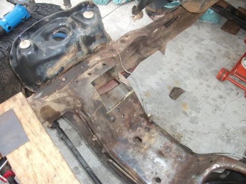1990 Ford Bronco - A heavily rusted vehicle frame is shown, with a blue grinder and other tools in the background.