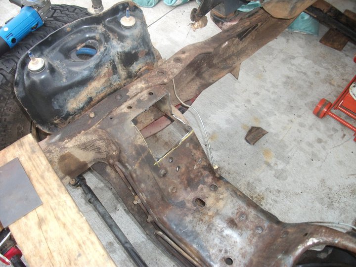 rusted vehicle frame with a blue grinder nearby