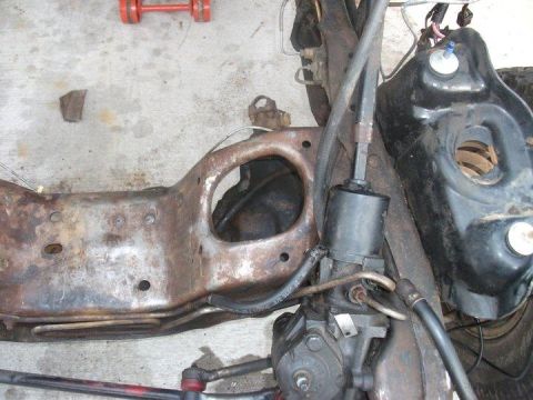 1990 Ford Bronco - Close-up of a heavily rusted vehicle frame section, showing steering components and hydraulic lines.
