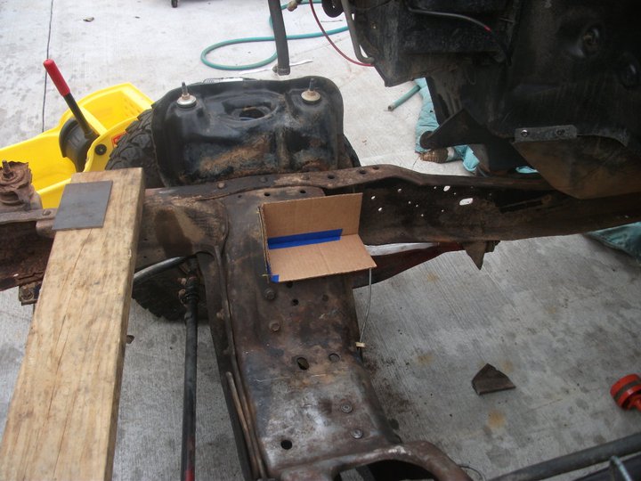 Vehicle frame with fuel tank removed, showing rust and some support structures