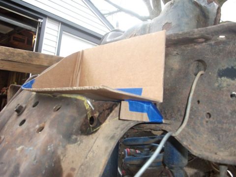 1990 Ford Bronco - A cardboard template is taped to a rusty vehicle frame, obscuring the suspension and engine bay area.