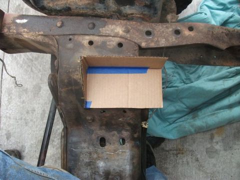 1990 Ford Bronco - A cardboard template is taped onto a rusty frame section, likely for a modification or repair.