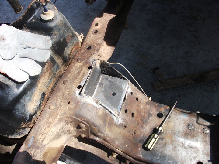 welding a metal bracket onto a heavily rusted vehicle frame, with a gloved hand visible