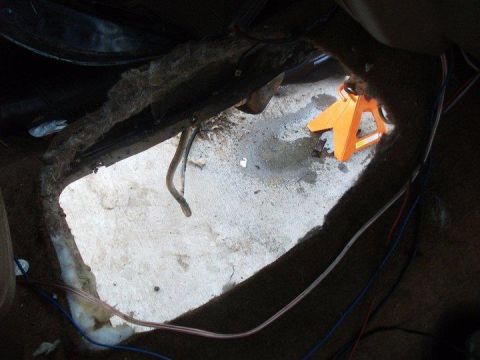 1990 Ford Bronco - A view of the interior floor with a large opening revealing the undercarriage and an orange jack stand.
