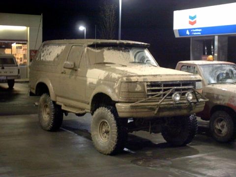 1995 Ford Bronco - This heavily mud-covered 1995 Ford Bronco appears to have seen some off-road action, parked at a gas station.
