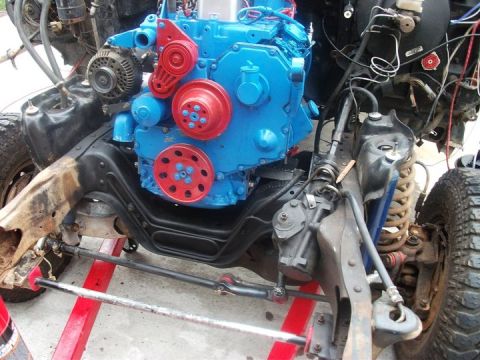 1990 Ford Bronco - A blue and red engine is installed in a vehicle chassis, likely undergoing an engine swap.