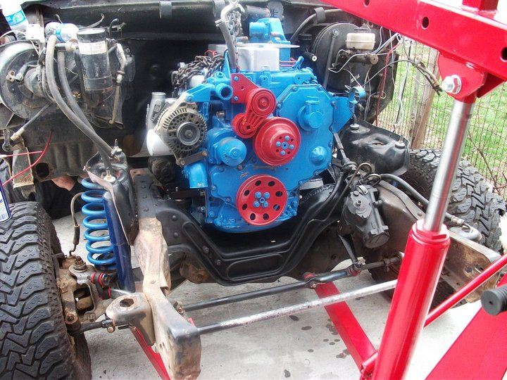 engine hoist lifting blue and red engine into vehicle frame