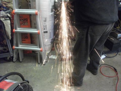 1990 Ford Bronco - Sparks fly as someone uses an angle grinder in a workshop setting.