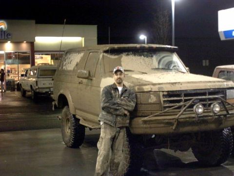 1995 Ford Bronco - Man poses with a mud-caked Ford Bronco, another truck visible behind.